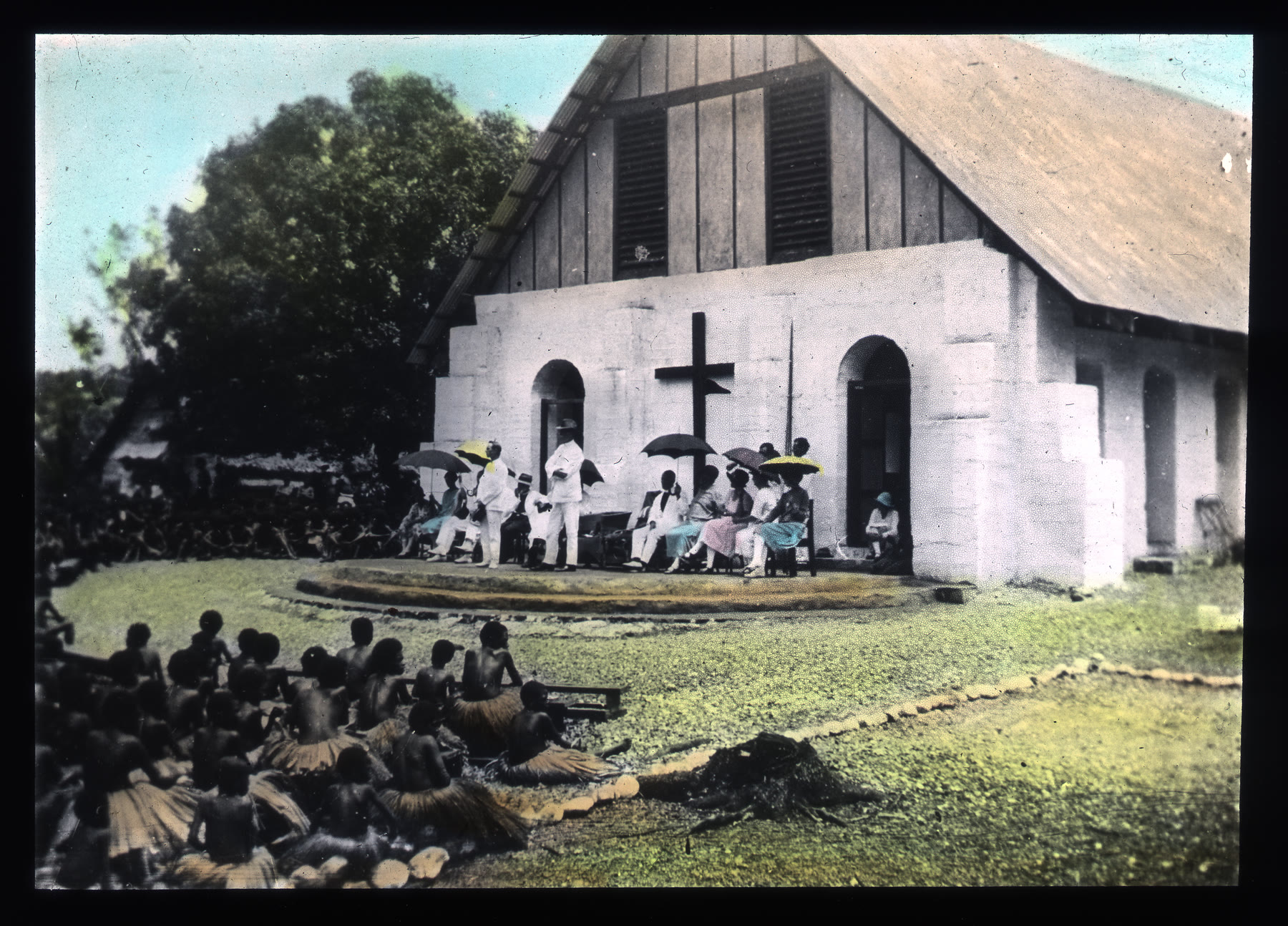 Archival black-and-white view of All Saints Church at Boianai mission, with its steep roof and cross standing among tropical vegetation.