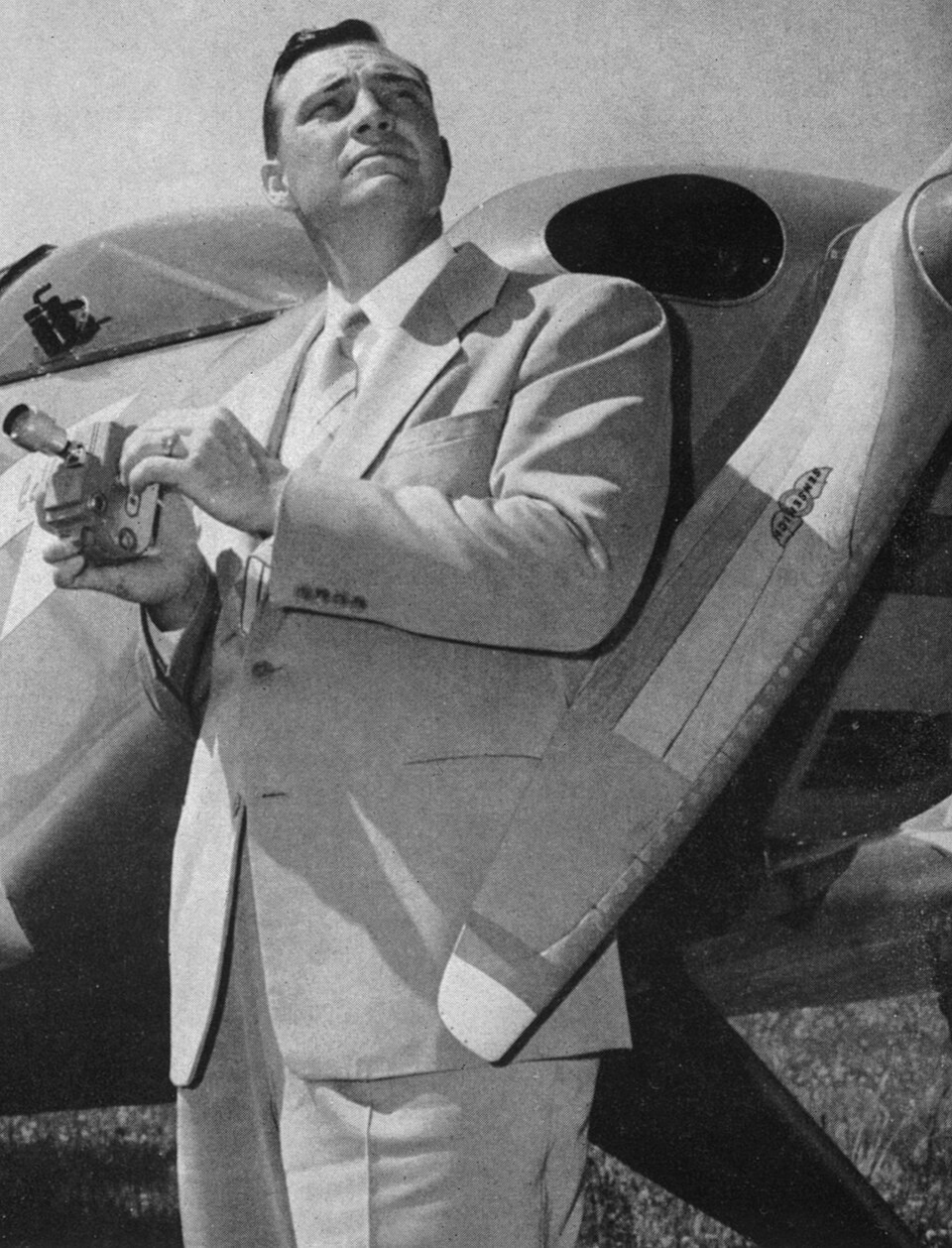 Kenneth Arnold standing beside an airplane and holding a camera in 1947.